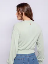 Cárdigan corto color beige, de manga larga y escote en V. Tiene cuatro botones brillantes.