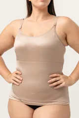 Camiseta modeladora color piel, confeccionada en lycra reforzada con tela de faja en la zona abdominal. Cuenta con breteles regulables y escote redondo.