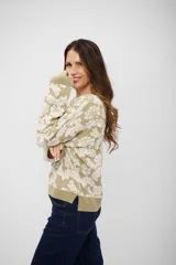 Buzo de tejido de punto con diseño floral en tonos beige y crema, de corte holgado, cuello redondo y mangas largas con puños acanalados.