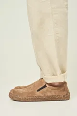 Championes slip-on color arena, con capellada de gamuza y elásticos laterales negros. La suela es fina, flexible y plana, con un diseño que simula corcho.