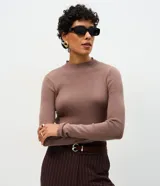 Suéter de punto canelado color marrón, con cuello alto y manga larga. Presenta un diseño ajustado al cuerpo, sin costuras aparentes, confeccionado en una mezcla de viscosa, poliéster y poliamida.