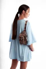 Riñonera color beige con textura de piel de cocodrilo, correa ajustable y cierre con cremallera.