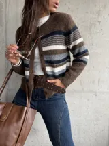 Saco tejido de punto con diseño a rayas horizontales en tonos marrón, blanco y gris. Presenta cuello redondo, cierre frontal con botones y mangas largas.