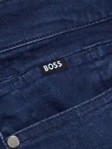 Jeans de corte ajustado en denim azul oscuro, con etiqueta de la marca Boss cosida en el bolsillo trasero y remaches metálicos grabados.