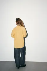 Camisa oversize color amarillo pastel, con cuello solapa, manga larga con puño y cierre frontal con botones.