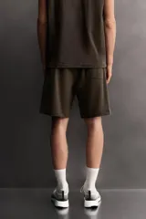 Short jogger marrón de corte relaxed fit, confeccionado en tejido compacto de algodón, con cintura elástica ajustable, bolsillos frontales en la cadera y bolsillo trasero de plastrón.
