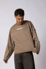 Buzo oversize de corte boxy, confeccionado en algodón rústico de alto gramaje en color beige. Presenta cuello redondo con borde crudo, mangas largas y una estampa frontal con el texto VCP delimitado por líneas horizontales blancas.