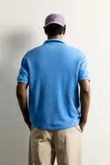 Sudadera polo regular fit de manga corta color mostaza, confeccionada en tejido con mezcla de algodón e interior de rizo, con cuello solapa y cierre frontal de botonadura.