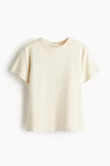 Remera de algodón en color beige, de corte clásico y manga corta, con cuello redondo acanalado.