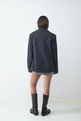 Blazer de corte recto en color gris oscuro, con cuello de solapa, cierre frontal de dos botones y bolsillos laterales con solapa. Cuenta con forro interior.