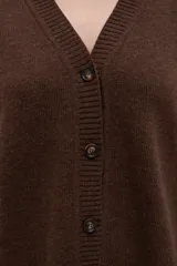 Cárdigan color crema de tejido de punto industrial con escote en V, combinación de puntos y botones decorativos en las mangas.