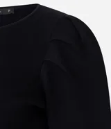Cardigan de punto negro con cuello redondo, mangas largas abullonadas y cierre frontal con botones decorativos en forma de flor dorada. Presenta un corte corto y ajustado.