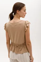 Remera de algodón y lyocell color beige, con cuello redondo, mangas cortas con volados y detalle de frunce con volado en la cintura.