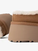 Zueco marrón de cuero con forro de piel sintética color crema. Tiene plataforma y suela de goma.