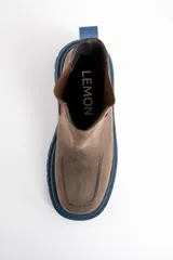 Bota tipo Chelsea de cuero lavado en tono marrón, con paneles laterales elásticos en color marrón oscuro. Presenta una suela track robusta de goma en color azul y un tirador trasero en el mismo tono azul.
