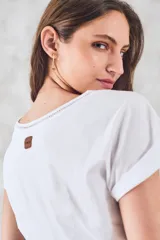 Remera negra de algodón peinado, ajustada al cuerpo, con cuello redondo y detalles de vainillas caladas en el escote y los hombros. Las mangas son cortas y están dobladas hacia afuera.