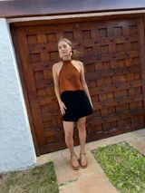 Top halter confeccionado en cuero color camel, con diseño sin mangas, espalda descubierta y ajuste mediante tiras.