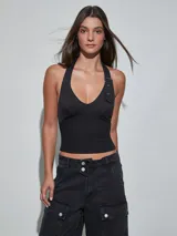 Top halter negro con detalle de tira y hebilla metálica en el hombro, con escote en V pronunciado y corte ajustado.