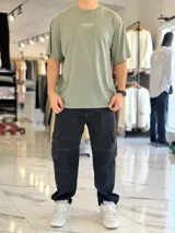 Remera oversize de color verde militar, con gran estampado tipográfico blanco en la espalda y mangas cortas.