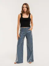 Pantalón de jean elastizado azul con terminación metalizada, corte wide leg, tiro medio, cierre delantero con botón, bolsillos laterales y traseros.