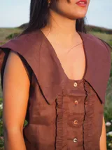 Blusa sin mangas de lino color blanco, con cuello marinero grande y detalles de encaje en el cuello y a lo largo de la botonadura frontal.