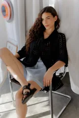 Saco calado negro tejido a máquina, con cuello tipo camisa y mangas 3/4.