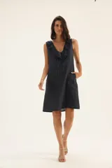 Vestido azul marino de lino, corte recto, sin mangas, con escote en V con volados y cordón ajustable.