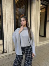 Poncho de hilo liviano en color gris, con cuello alto y diseño de caída fluida y asimétrica.