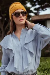 Camisa celeste de manga larga con cuello mao y volados frontales.