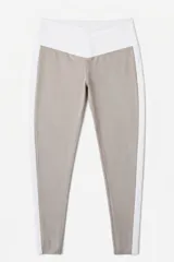 Calza deportiva de tiro alto con diseño de paneles en contraste, combinando color beige y blanco. Presenta una banda lateral blanca que recorre toda la pierna y una cintura ancha en forma de V.