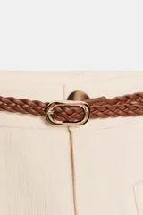 Pantalón culotte de tiro medio color crema, con pierna ancha y bolsillos de plastrón en el frente. Incluye un cinturón trenzado marrón.