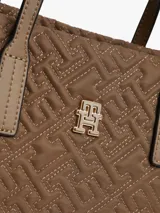 Cartera tipo tote de Tommy Hilfiger, confeccionada en nailon reciclado color marrón con diseño acolchado de monograma TH. Cuenta con dos asas superiores, cierre de cremallera y logo metálico distintivo en la parte frontal.
