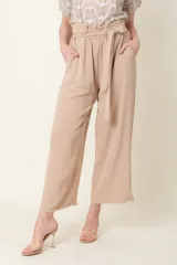 Pantalón ancho color beige, con cintura elastizada con lazo y bolsillos laterales. Tiro alto y volado en la cintura.