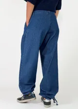 Pantalon de denim azul de corte holgado, con cintura elástica y puños ajustables con cordones en los tobillos.