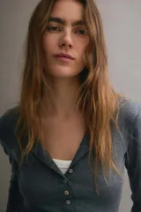Saco en tejido liviano gris oscuro melange, con cuello redondo, manga larga y cierre frontal abotonado con numerosos botones pequeños.
