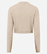 Cardigan corto de punto con textura atoallada, cuello redondo y cierre frontal con botones. Presenta mangas largas con puños acanalados, dos bolsillos delanteros funcionales y bajo acanalado para un mejor ajuste.