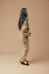 Pantalón de cuero color marrón con estampado abstracto, corte acampanado y abertura en el ruedo.