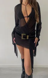 Minivestido negro de microtul transparente con corte irregular y mangas largas.