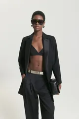 Saco largo sastrero negro de lana fría, corte recto, con cuello y solapa, botones en el delantero y en los puños.