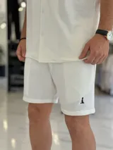 Bermuda blanca de tejido texturizado, con pequeño bordado oscuro en la parte inferior izquierda.