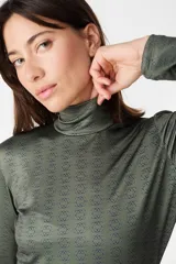 Polera de cuello alto y manga larga, confeccionada en tejido de poliéster con estampado geométrico repetitivo en tonos verde oliva y negro.