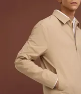 Campera de sarga color beige con cuello inglés, cierre frontal de cremallera, mangas largas y bolsillos laterales. Diseño minimalista y versátil con forro interior.