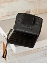 Billetera pequeña de cuero negro con textura de cocodrilo y cierre de cremallera.