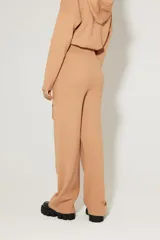 Pantalón tejido color beige, de calce relaxed, con elástico en la cintura, lazo incorporado y bolsillos delanteros.