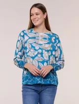 Blusa de silueta holgada y corte recto con caída fluida, escote redondo y mangas largas con puños anchos estructurados, con estampado floral en tonos pasteles sobre fondo blanco.