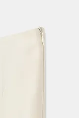 Falda midi de tiro medio, color blanco off-white, confeccionada en hilatura de viscosa. Presenta un diseño fluido, con bajo asimétrico y detalle de caída drapeada en el lateral. Cierre con cremallera oculta en costura.