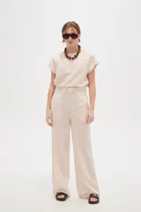 Pantalón de viscosa color beige, de diseño ancho y tiro alto con detalle de plisado en la cintura.