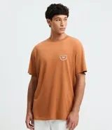 Remera masculina color marrón, de corte comfort, con cuello redondo y mangas cortas. Presenta un estampado de letras "Travelers" en el pecho y la espalda.