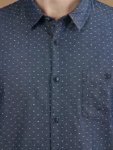 Camisa de manga larga azul con pequeños lunares blancos, cuello clásico y bolsillo en el pecho.