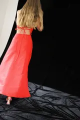 Vestido verde oliva de satén, con corte irregular, un hombro descubierto, abertura lateral y nudo decorativo en la cintura.